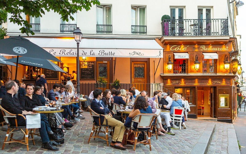 Khám phá Montmartre Paris – Nơi nghệ thuật, lịch sử và tình yêu giao hòa 6 Enjoying Drinks And Lively Conversations At A Charming Café In Montmartre, Paris